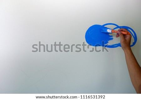 Hand drawing cloud symbol on a white wall, isolated on white background. Stock photo of hand of painter painting or drawing blue cloud on white board or wall. Copy space, blank space