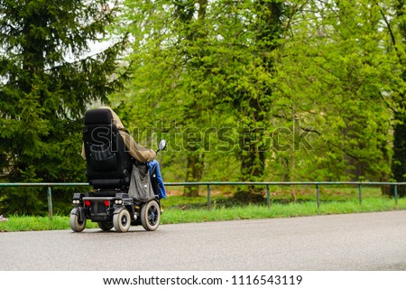 Unidentified disabled person in an electric wheelchair outdoors Royalty-Free Stock Photo #1116543119