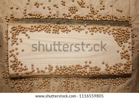 Piece of raw wood with chikpea on crumpled brown paper background. Top view, space for text.