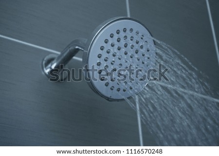 Shower head in bathroom with water drops flowing.  