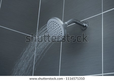 Shower head in bathroom with water drops flowing.

