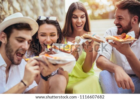 Happy people eating fast food in city while travelling