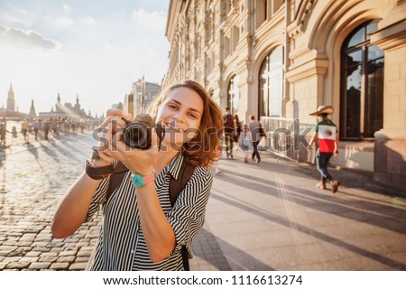 Beautiful happy smiling woman woman traveler with camera in hands on summer street