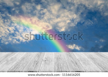 Cloudscape rainbow of natural sky with blue sky and white clouds and colorful rainbow in the sky with wood table or terrace use for wallpaper background