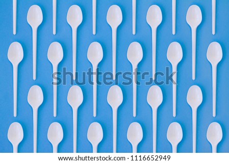 Flay lay photo of white plastic disposable spoons. Creative top view pattern. Calm clear colours.