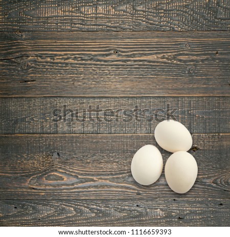 Three white whole eggs on wooden table top view with copyspace. Template mock up with countertop for natural eco product advertising