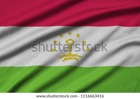 Tajikistan flag  is depicted on a sports cloth fabric with many folds. Sport team banner