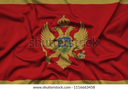 Montenegro flag  is depicted on a sports cloth fabric with many folds. Sport team banner