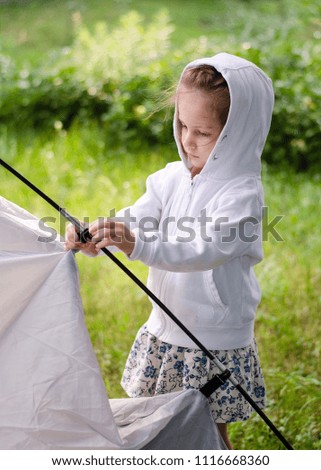 Little girl is setting up a tent.  Children's tourism.