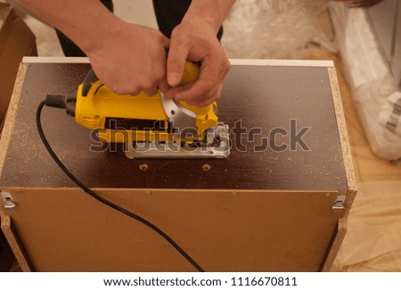 Wood worker cutting wooden panel with jig saw. DIY worker cutting wooden panel with jig saw