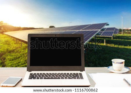 Mockup image of laptop with blank white screen,smartphone,coffee cup on wooden table of solar panel on blue sky background, Alternative energy concept,Clean energy,Green energy.
