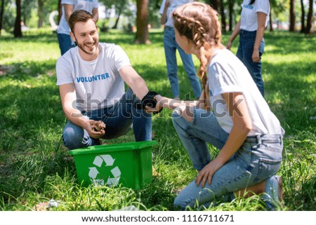 happy volunteers cleaning lawn with green recycling box