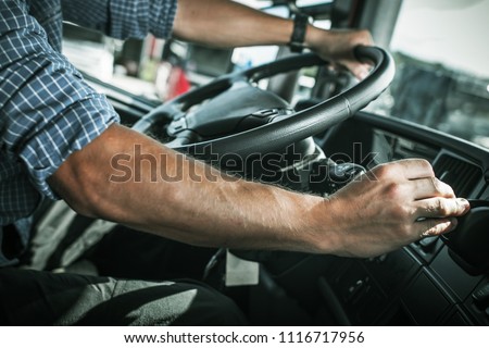 Caucasian Truck Driver Behind the Wheel of Semi Truck. Transportation Industry Theme. CDL Driver. Royalty-Free Stock Photo #1116717956