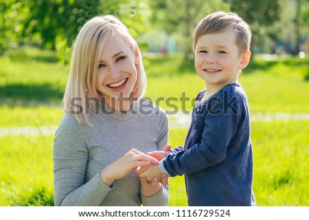 beautiful mother wipes hands with napkins of cute baby (son) in the park on a background of green grass and trees
