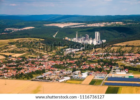 Bird eye perspective view of european town surrounded with fields and forests with industrial factory and solar panels