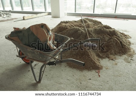 a wheelbarrow and a pile of sand at a construction site