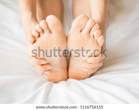 Close up photo of a female feet. Woman massaging her feet on the bed.