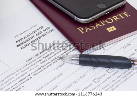 An application sheet for immigrant visa and alien registration to the United States of America. A photo of a foreign passport and a black pen. 