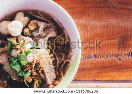 The Noodles Tom Yum soup. Put the pork green leafy vegetables and beans are placed on the wooden table Brown