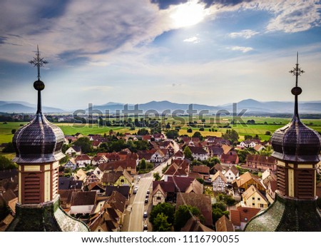 Soaring majestic church Saint Maurice in little french village Ebersmunster. Aerial drone view. Alsace. France. Royalty-Free Stock Photo #1116790055