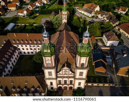 Soaring majestic church Saint Maurice in little french village Ebersmunster. Aerial drone view. Alsace. France. Royalty-Free Stock Photo #1116790061