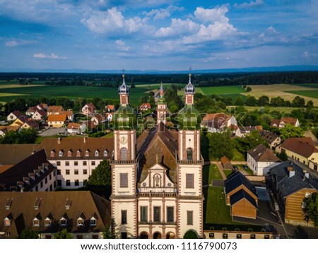 Soaring majestic church Saint Maurice in little french village Ebersmunster. Aerial drone view. Alsace. France. Royalty-Free Stock Photo #1116790073