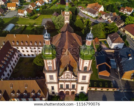 Soaring majestic church Saint Maurice in little french village Ebersmunster. Aerial drone view. Alsace. France. Royalty-Free Stock Photo #1116790076
