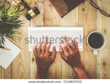 Top view man typing keyboard freelancer working at his desk table with business object.