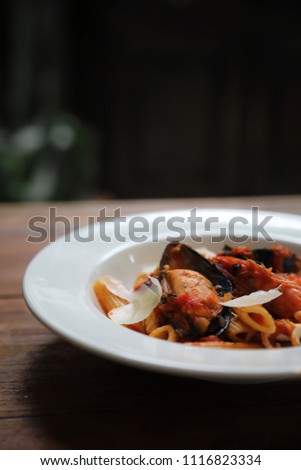 Penne pasta tomato sauce arabiata with seafood on wood background vintage style