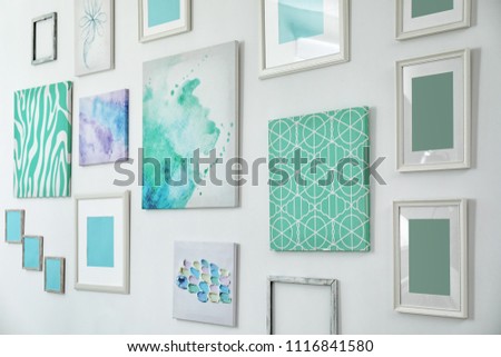 Many abstract mint paintings on light wall