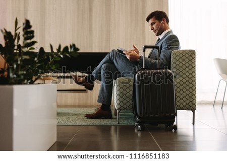 Businessman reading a magazine while waiting for his flight at airline terminal lounge. Entrepreneur at airport waiting area reading a magazine. Royalty-Free Stock Photo #1116851183