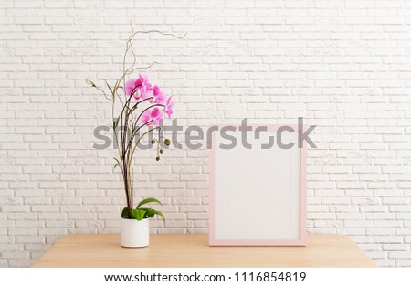 Blank pink picture frame template for place image or text inside with a little tree on wood table.