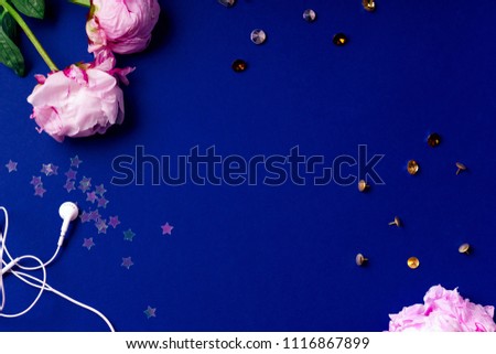 Flat lay composition with peons, sparkles and accessories on blue background. Top view, colorful workspace concept