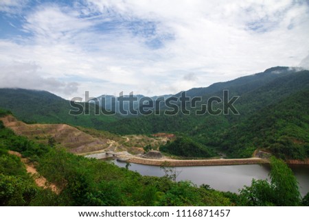 View of the dam reservoir in the middle of the valley and white clouds and blue sky background