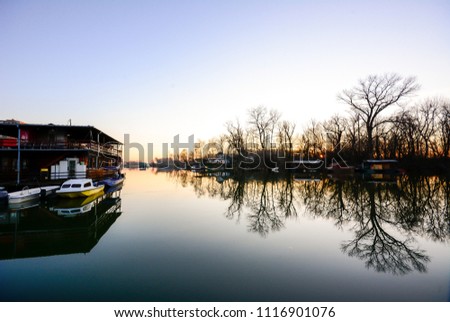 Sunset on the river with a relaxing view of the calm water, boats and rafts. Wide angle, landscape, background. Reflection of forests and boats, rafts in clean water.