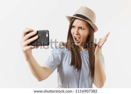 Irritated dissatisfied woman in blue dress, hat doing selfie shot on mobile phone or video call isolated on white background. People, sincere emotions, lifestyle concept. Advertising area. Copy space