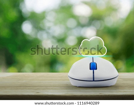 Cloud icon with copy space and wireless computer mouse on wooden table over blur green tree in park, Cloud computing concept