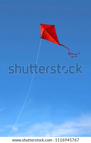 A red kite flying against a vivid blue sky Royalty-Free Stock Photo #1116945767