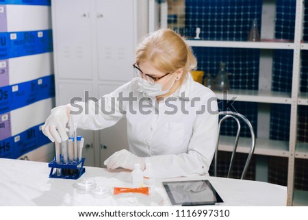 a focused student-science works in a lab with a test tube. The girl chooses the right test tube