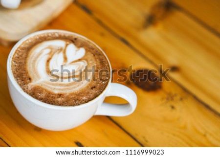 Beautiful Latte art coffee with foam milk tree picture, placed on the wooden table background.