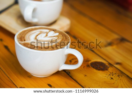 Beautiful Latte art coffee with foam milk tree picture, placed on the wooden table background.