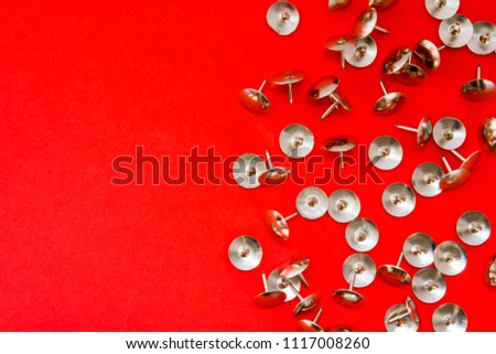 Metal shiny sharp pins or thumbtracks scattered on red background with clean area of photo for labels or headers. Symbol of symptom of acute pain, disease, hemorrhoids in proctology, dangers, hard way