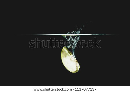 Part of fruit, Fresh and delicious green apple isolated against dark, black background. green apple dropping in water and creating a splash. The concept of healthy eating, consuming fruit.
