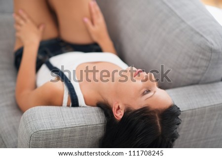 Thoughtful young woman laying on couch