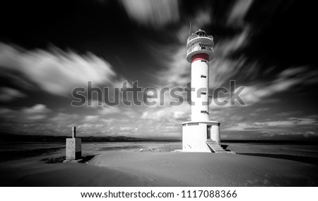 B&W picture of Far del Fangar lighthouse, with clouds in motion.