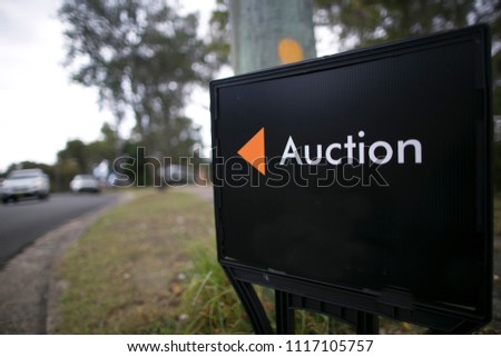 Black auction sign board installed and advertising by estate agency on the public street downtown Sydney city CBD, Australia  
