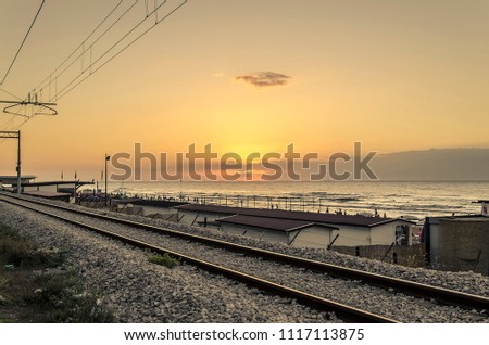 Coastal landscape with railway and sunset on the sea