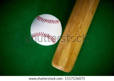 White Baseball ball and wooden bit isolated on green felt background