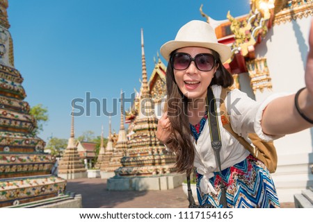 Asian woman walking in the narrow alley of the ancient temple surrounded by the heritage. She is talking a selfie photo.