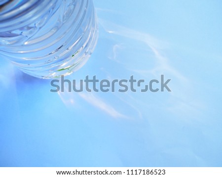 Top view Bottle bottom plastic water with sunlight on blue background